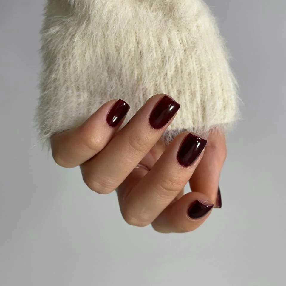 Deep burgundy gel nails on a client at Nailed It Studio Rīga